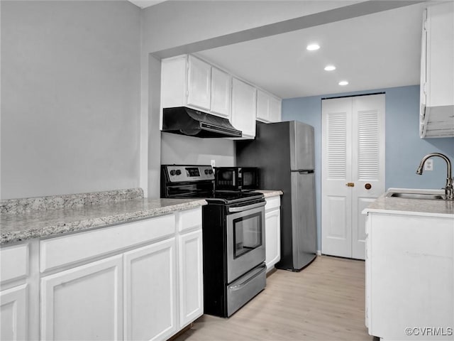 kitchen featuring stainless steel appliances, light wood-type flooring, light stone countertops, sink, and white cabinetry