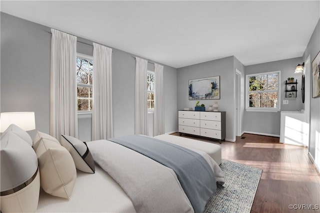 bedroom with multiple windows and dark hardwood / wood-style floors