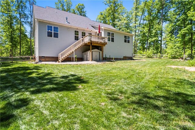 rear view of house with a yard, a deck, and a storage shed