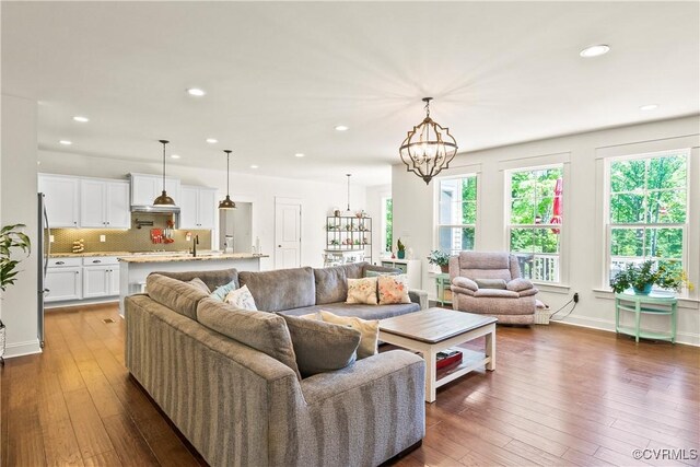 living room with dark hardwood / wood-style floors, sink, and a chandelier