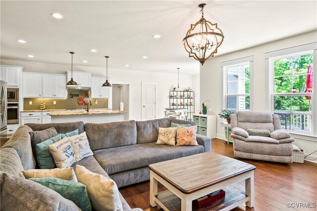 living room with dark wood-type flooring, a wealth of natural light, and a chandelier