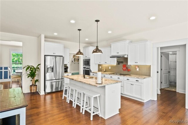 kitchen with white cabinetry, light stone countertops, black appliances, an island with sink, and decorative light fixtures