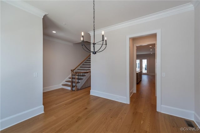 unfurnished dining area featuring light wood-type flooring, an inviting chandelier, and ornamental molding