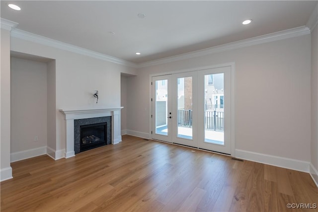 unfurnished living room with ornamental molding, french doors, and light hardwood / wood-style flooring