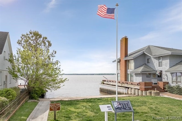 view of dock with a water view and a lawn