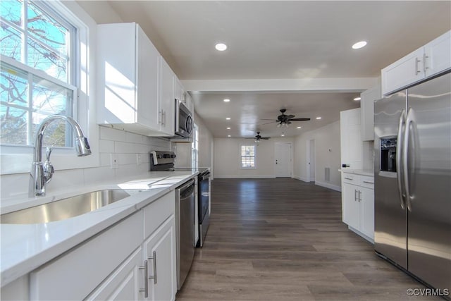 kitchen with tasteful backsplash, stainless steel appliances, ceiling fan, sink, and white cabinets