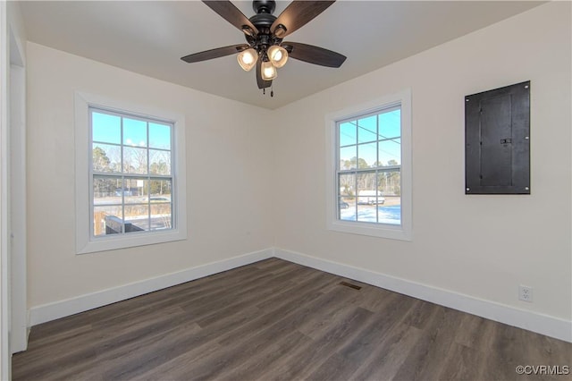 empty room with electric panel, ceiling fan, plenty of natural light, and dark hardwood / wood-style floors