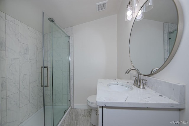 bathroom featuring vanity, toilet, and a shower with shower door