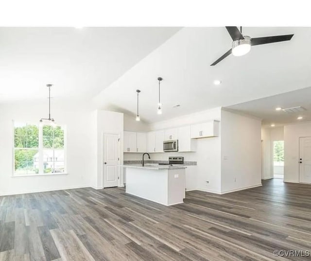 kitchen featuring decorative light fixtures, white cabinetry, a center island with sink, and stainless steel appliances