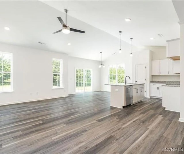 kitchen with an island with sink, hanging light fixtures, vaulted ceiling, stainless steel dishwasher, and white cabinets