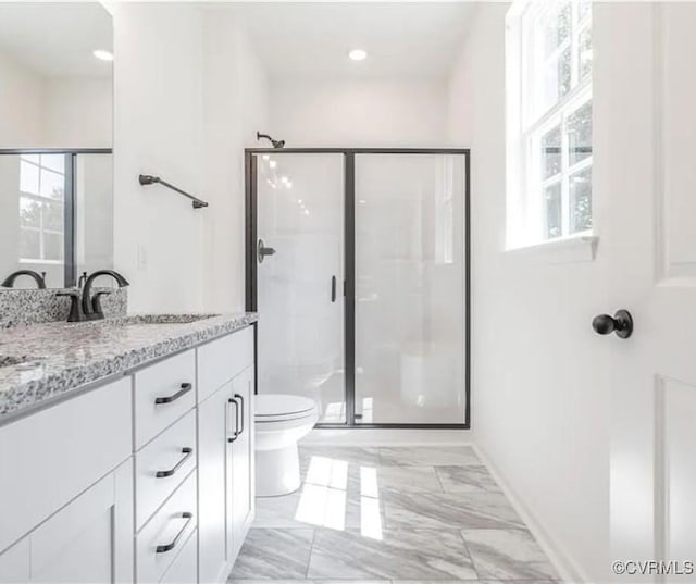 bathroom with an enclosed shower, vanity, toilet, and a wealth of natural light