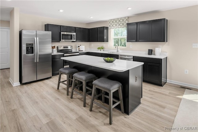 kitchen featuring a center island, appliances with stainless steel finishes, a kitchen breakfast bar, and light hardwood / wood-style floors