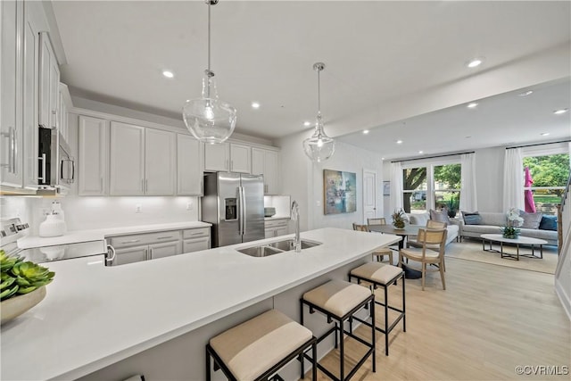 kitchen with appliances with stainless steel finishes, decorative light fixtures, white cabinetry, and sink