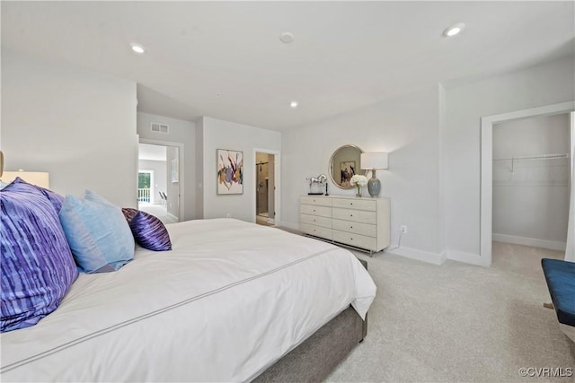 bedroom featuring light carpet, a walk in closet, and a closet