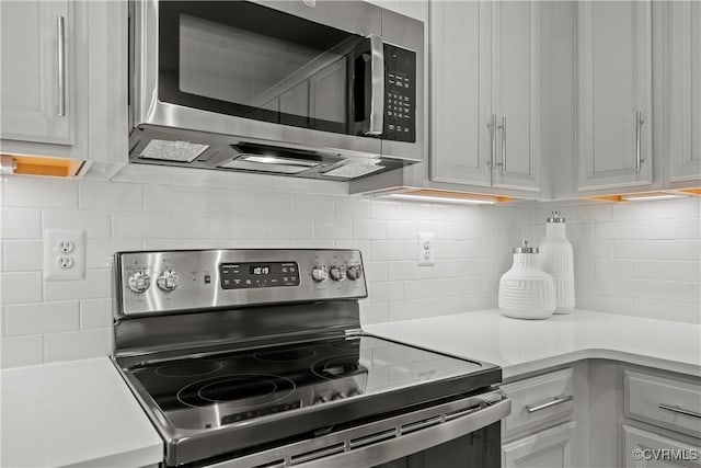 kitchen with decorative backsplash, stainless steel appliances, and white cabinets