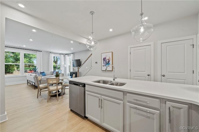 kitchen with dishwasher, decorative light fixtures, light hardwood / wood-style flooring, and sink