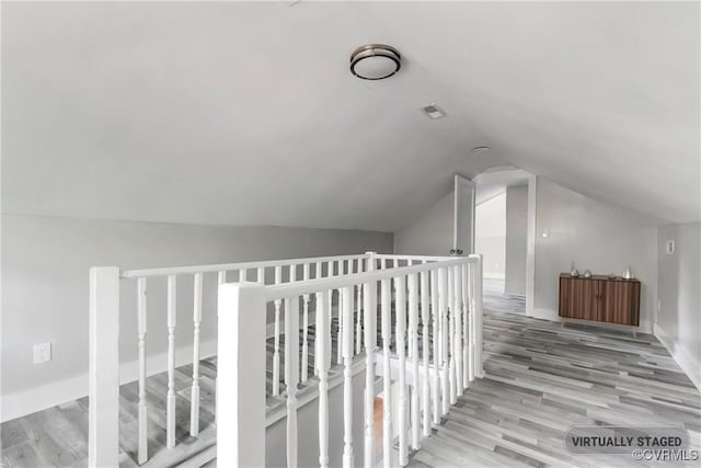 hall featuring light wood-type flooring and vaulted ceiling