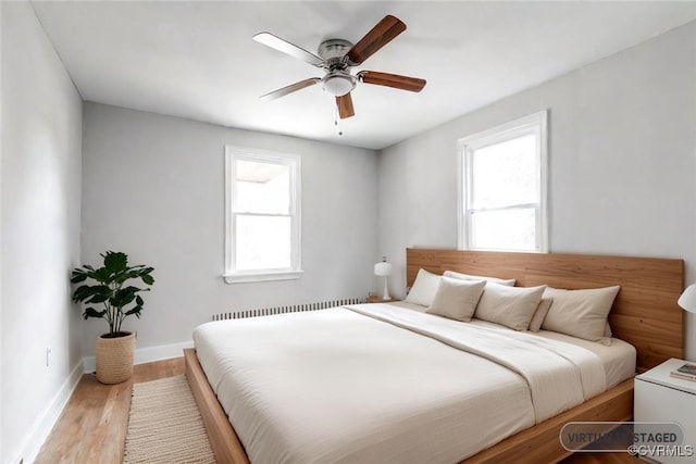 bedroom featuring ceiling fan, light wood-type flooring, and radiator heating unit