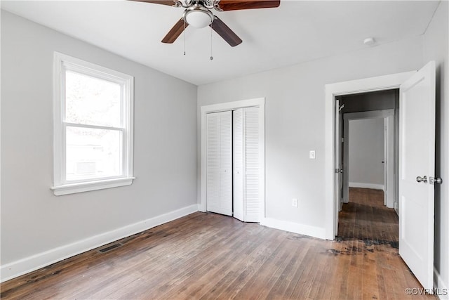 unfurnished bedroom with ceiling fan, a closet, and dark wood-type flooring