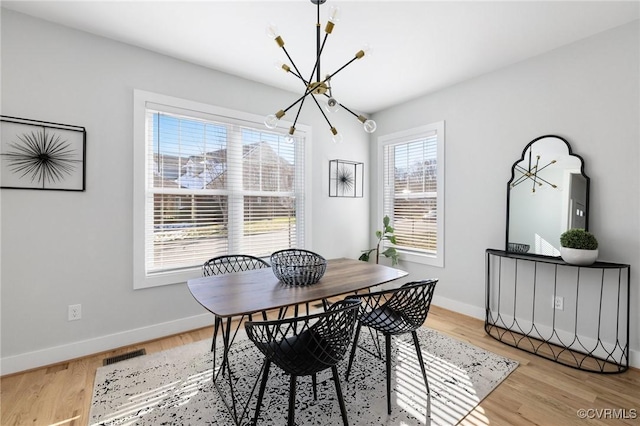 dining area with a notable chandelier and light hardwood / wood-style flooring