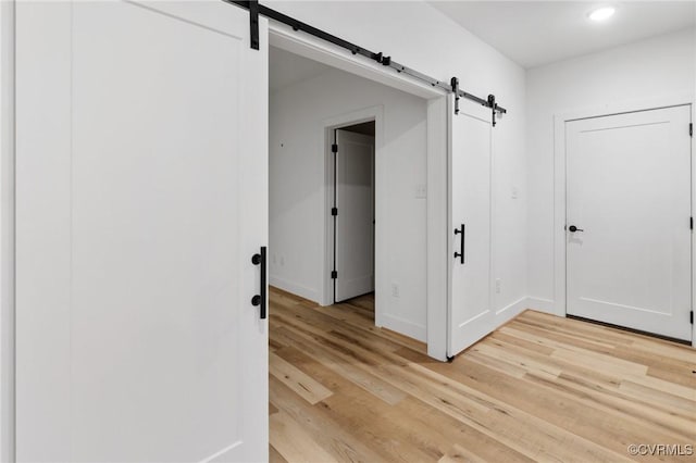 hall with light hardwood / wood-style floors and a barn door