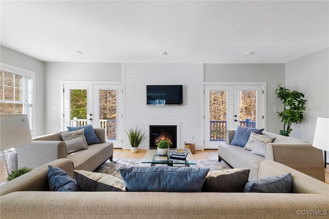 living room featuring light hardwood / wood-style flooring, french doors, and a fireplace