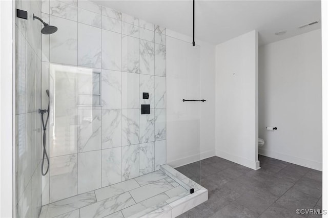 bathroom featuring tiled shower and toilet