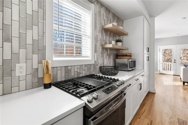 kitchen featuring appliances with stainless steel finishes, backsplash, a healthy amount of sunlight, and white cabinetry