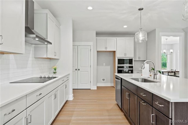 kitchen featuring dark brown cabinets, sink, wall chimney range hood, decorative light fixtures, and white cabinetry