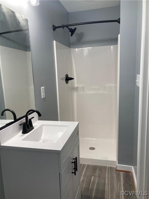 bathroom with hardwood / wood-style flooring, vanity, and a shower