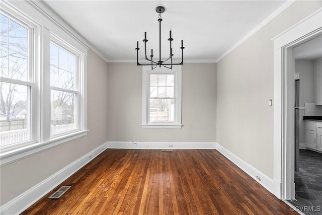 unfurnished dining area featuring a notable chandelier, a wealth of natural light, and crown molding