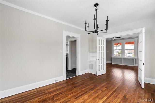 unfurnished dining area with french doors, dark wood-type flooring, ceiling fan with notable chandelier, and ornamental molding