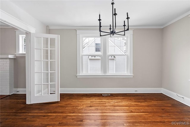 unfurnished dining area with dark wood-type flooring, ornamental molding, and an inviting chandelier