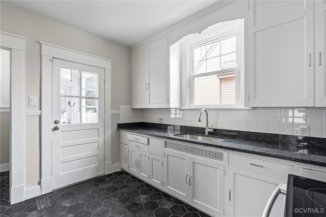 kitchen featuring backsplash, dark stone countertops, sink, range with electric stovetop, and white cabinets