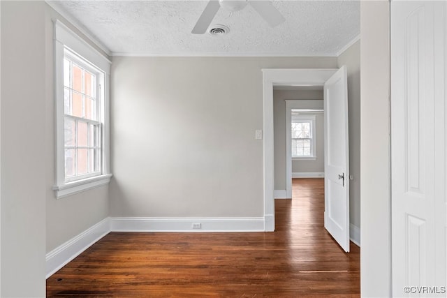 empty room with ceiling fan, a textured ceiling, dark hardwood / wood-style floors, and crown molding