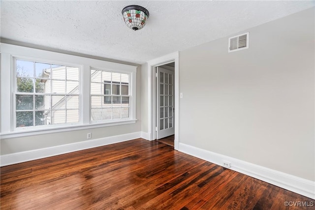 unfurnished room featuring dark wood-type flooring and a textured ceiling