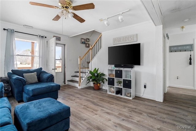 living room with ceiling fan, rail lighting, wood-type flooring, and crown molding