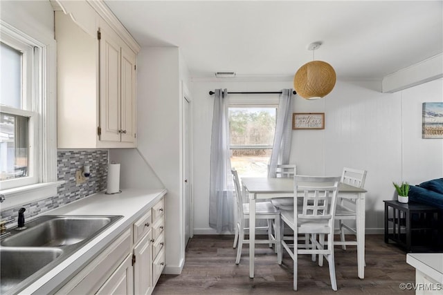 kitchen featuring sink, backsplash, dark hardwood / wood-style floors, and hanging light fixtures