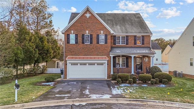 view of front of property featuring a garage, cooling unit, a front lawn, and covered porch