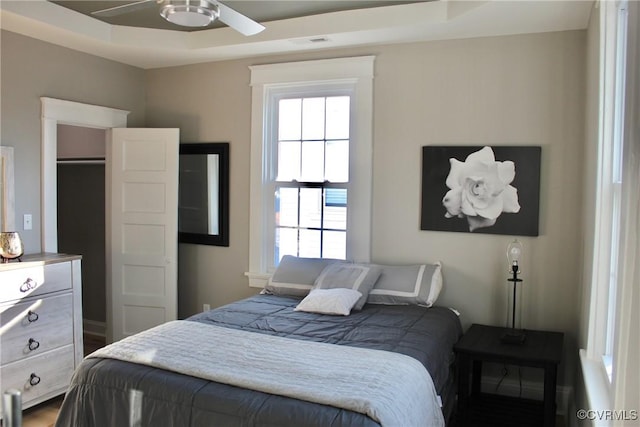 bedroom with ceiling fan and a tray ceiling