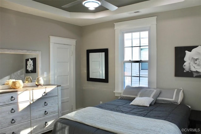 bedroom with ceiling fan and a raised ceiling