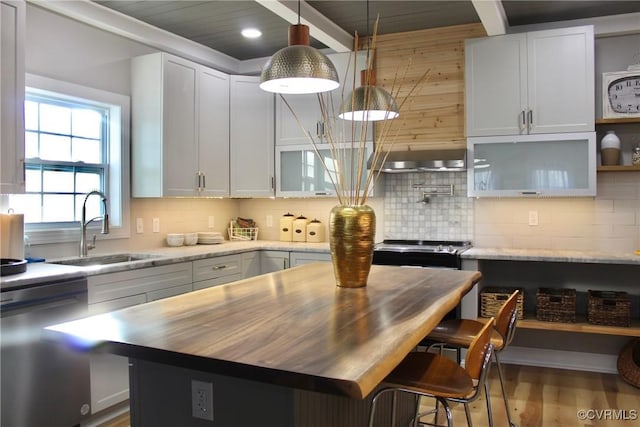 kitchen featuring decorative light fixtures, hardwood / wood-style floors, a kitchen island, white cabinets, and appliances with stainless steel finishes