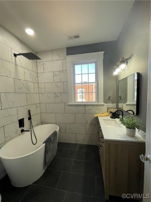 bathroom with tile walls, separate shower and tub, tile patterned floors, and vanity