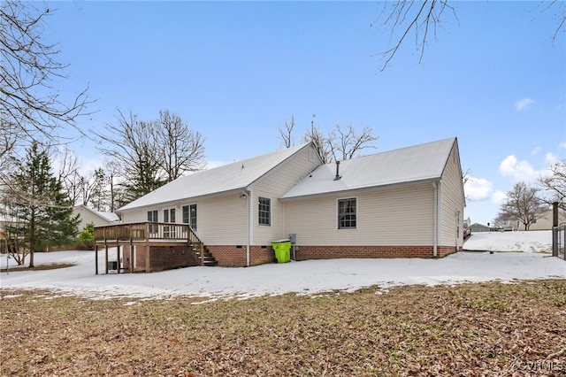 snow covered back of property featuring a deck