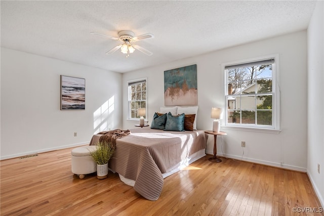 bedroom featuring a textured ceiling, light hardwood / wood-style floors, and ceiling fan