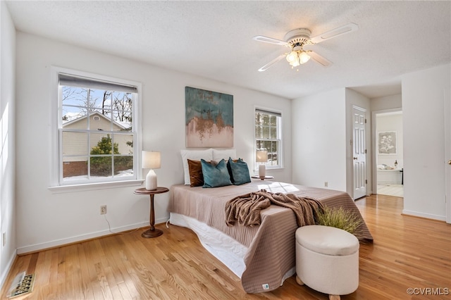 bedroom with ceiling fan, light hardwood / wood-style floors, and ensuite bathroom