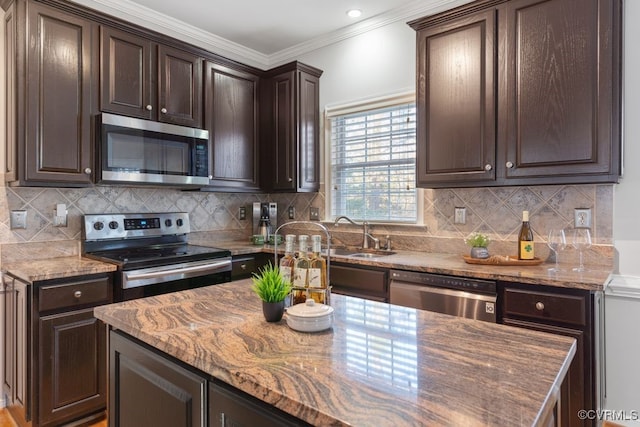 kitchen featuring light stone counters, sink, stainless steel appliances, crown molding, and dark brown cabinetry