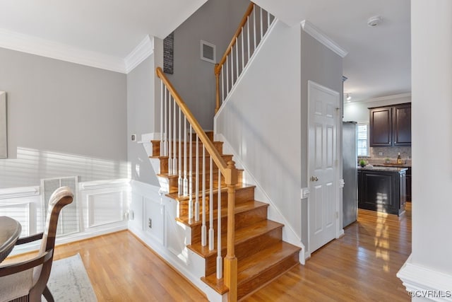 stairs with hardwood / wood-style floors and ornamental molding