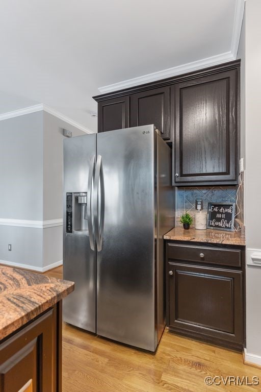 kitchen with ornamental molding, light wood-type flooring, stainless steel fridge, and dark brown cabinetry