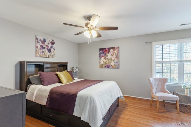 bedroom featuring ceiling fan, light hardwood / wood-style floors, and multiple windows